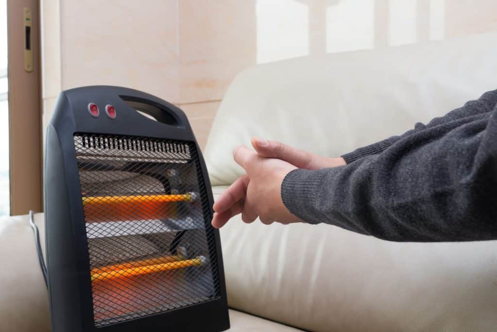 Person warming hands up next to portable heater