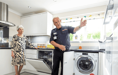 A safe and well tech and another person stood in a kitchen