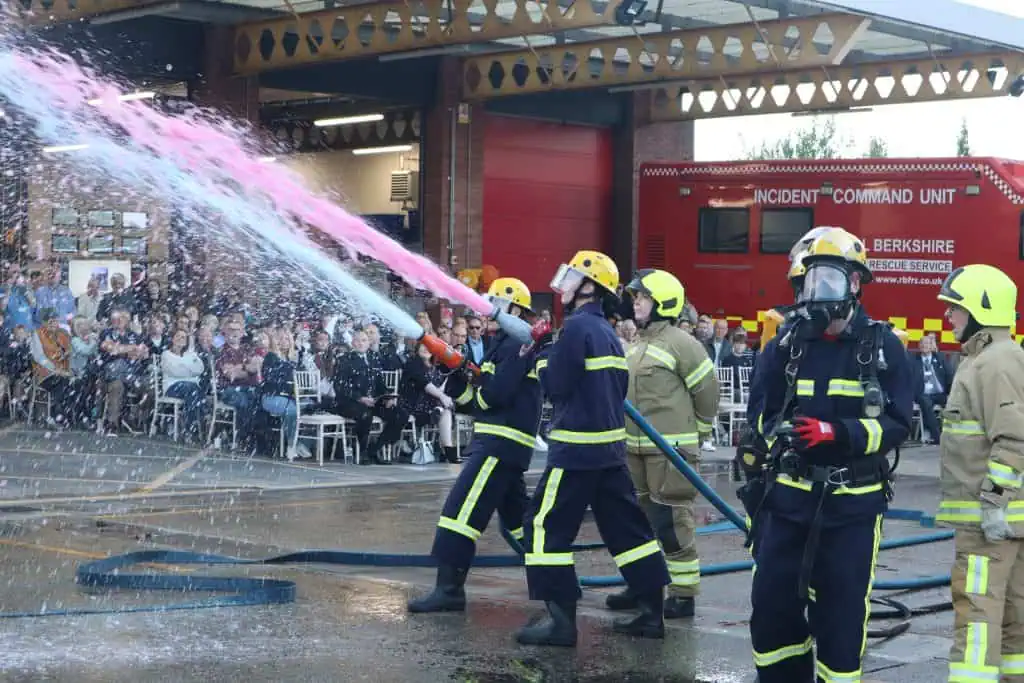 Two fire cadets using hose reels whilst others watch on.